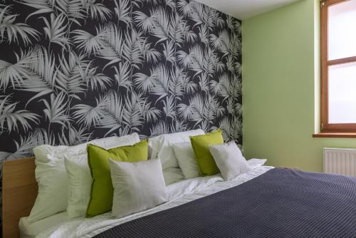 a bedroom with a bed with green and white pillows at Szent Margit Apartman in Veszprém