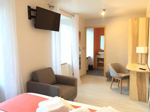 a living room with a couch and a television on a wall at Hôtel du Bout du Monde in Saint-Flour