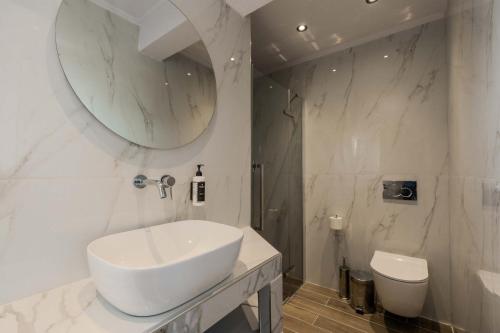 a white bathroom with a sink and a toilet at Orizon Apartments in Limenas