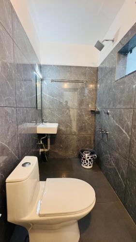 a bathroom with a white toilet and a sink at Real Casa in Anachal