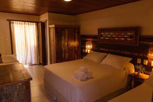 a bedroom with a large white bed with two towels on it at Pousada Casa de Praia in Praia do Forte