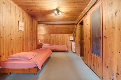 two beds in a room with wooden walls at Maison Les Rocailles in Saint-Martin-des-Combes