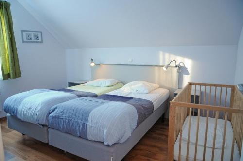 ein Schlafzimmer mit einem Bett und einem Kinderbett in der Unterkunft Villa Noach in Durbuy