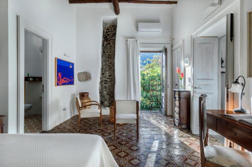 a bedroom with a bed and a desk and a window at Boutique Hotel I Cinque Balconi in Santa Marina Salina