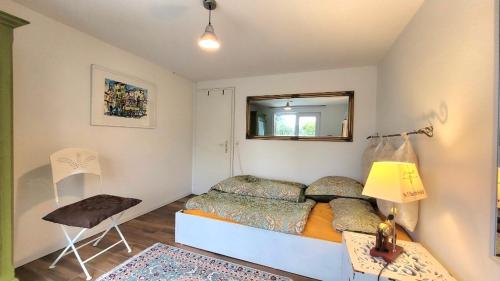 a bedroom with a bed and a mirror and a chair at Charmante Waldrandidylle in Kreuzlingen