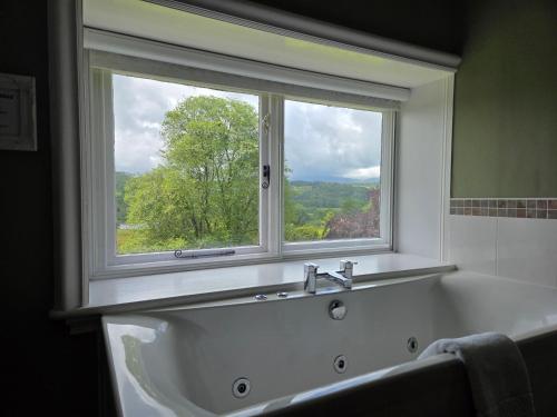 a bath tub with a window in a bathroom at Sawrey House in Near Sawrey