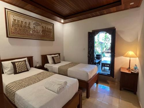 a hotel room with two beds and a window at Arsa Wayan Guest House in Klungkung