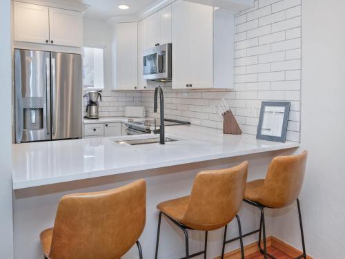 a kitchen with white cabinets and brown chairs at Ptarmigan Townhomes 30 in Vail