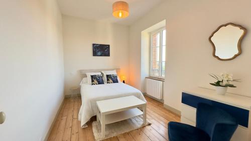 a small white bedroom with a bed and a table at Le Quai Granvillais in Granville
