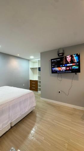 a bedroom with a bed and a flat screen tv on a wall at Chácara encantos Iranduba in Iranduba