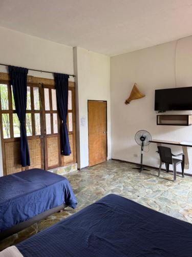 a bedroom with two beds and a flat screen tv at finca hotel palmas frente a panaca in Quimbaya