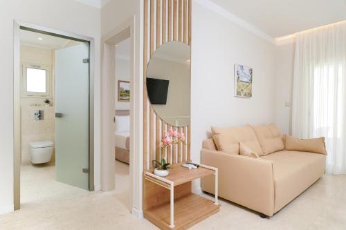 a living room with a couch and a mirror at Synthea Suites in Chrysi Ammoudia