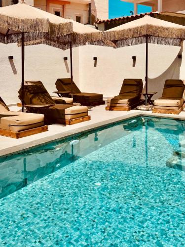a swimming pool with chairs and umbrellas at Hotel Mihasi in Ksamil