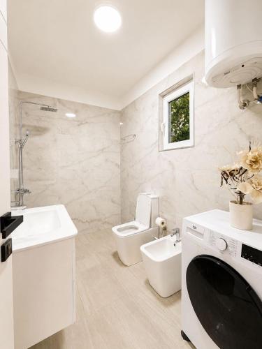 a white bathroom with a toilet and a sink at Deon in Vlorë