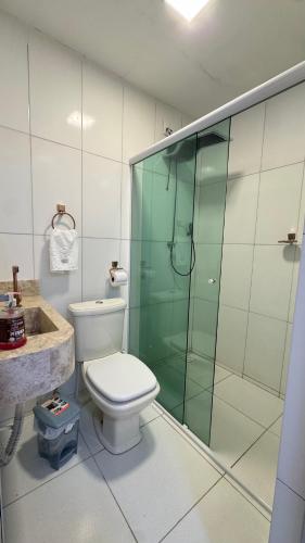 a bathroom with a toilet and a glass shower at Chácara encantos Iranduba in Iranduba