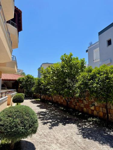 a brick wall with trees and bushes next to a building at Mihasi Apartments in Ksamil