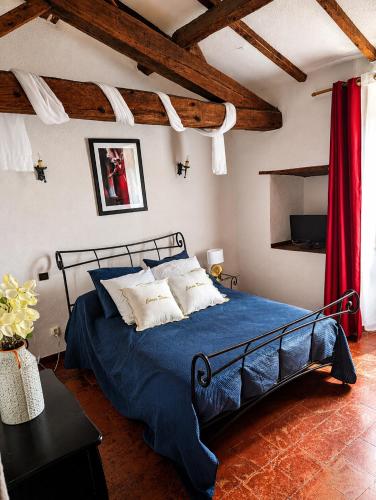a bedroom with a blue bed and a red curtain at Les Chambres Cast'elles in Malves