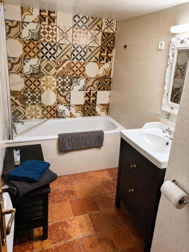 a bathroom with a bath tub and a sink at Les Chambres Cast'elles in Malves