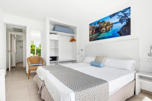 a bedroom with a bed and a tv on the wall at Hotel Chevy & Suites in Cala Ratjada