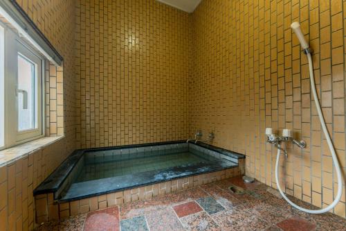 a bath tub in a yellow tiled bathroom at Kussharoko Artemina Deer in Teshikaga
