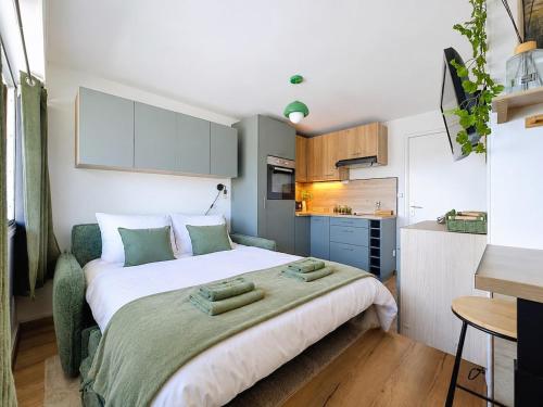 a bedroom with a large bed and a kitchen at Stella Plage, Studio Vert et Mer in Cucq