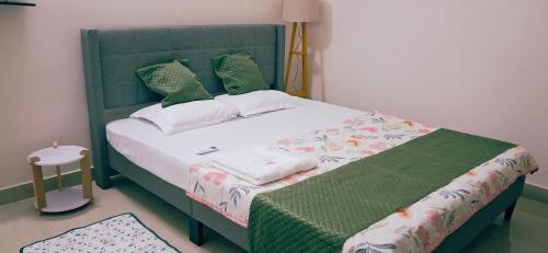 ein Bett in einem Schlafzimmer mit einem grünen Kopfteil in der Unterkunft Transit Nest 1BHK in Guwahati
