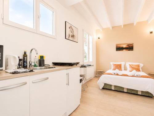 a white bedroom with a bed and a kitchen at Road Stop Studio - Paris - Disney- Train Station in Chelles