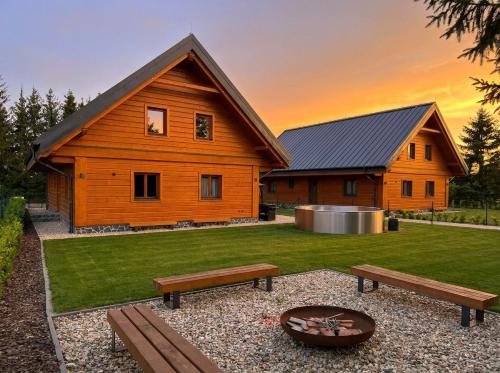 a wooden house with a fire pit and two benches at Chalupa Sandra in Vítějeves
