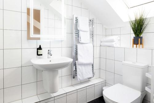 a white bathroom with a sink and a toilet at SACO Jersey - Merlin House in Saint Helier Jersey
