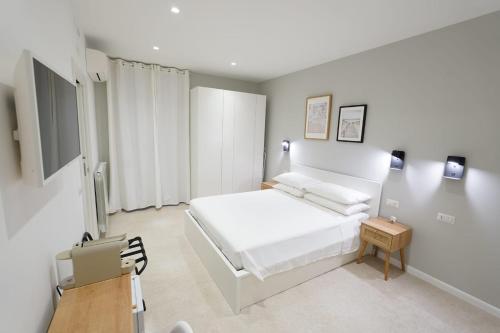 a white bedroom with a bed and a table at ResidenzaMarèa in Scalea