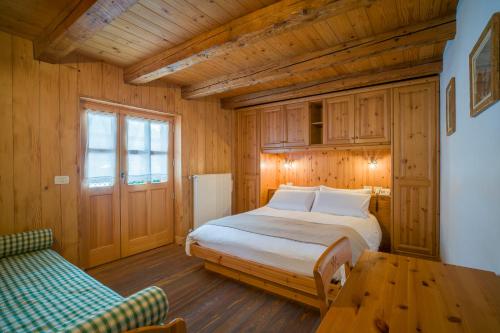 a bedroom with a bed and a table and a couch at Hotel Garni Plueme in Sauris