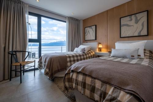 two beds in a hotel room with a large window at Costa Susana Ushuaia in Ushuaia