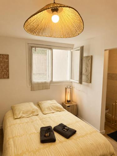 a bedroom with a bed with two black towels on it at Chambre Studio privé in Villenave-dʼOrnon
