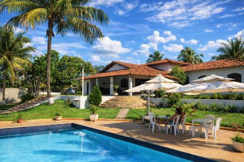 a woman sitting in a chair next to a house with a swimming pool at Pousada Doce Vida Guarapari in Guarapari