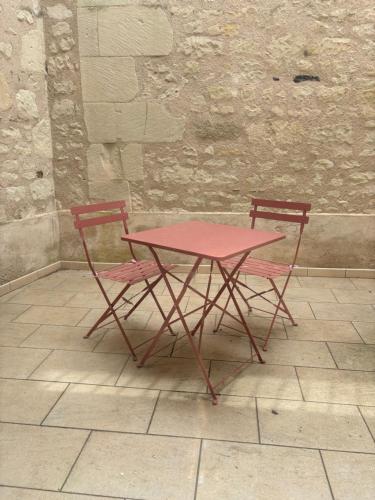 a red table and two chairs sitting next to a wall at nid douillet in La Roche-Posay