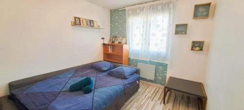 a bedroom with a bed with a blue comforter and a window at L'expérience quiétude espace modernité à Salles in Salles