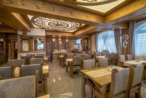 a restaurant with wooden walls and tables and chairs at Hotel Górski in Białka Tatrzanska