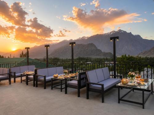 Eine Gruppe von Tischen und Stühlen auf einer Terrasse mit Blick auf den Sonnenuntergang in der Unterkunft Fialong Hotel Skardu in Skardu