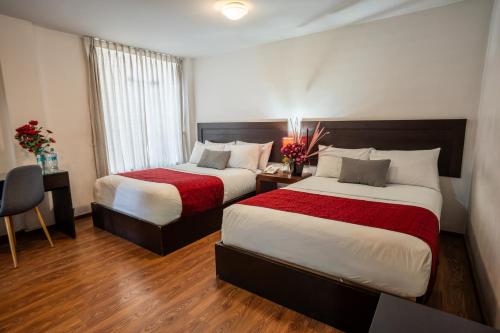 a hotel room with two beds and a desk at Hoteles Riviera Ejecutivo in Arequipa