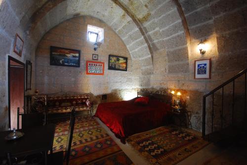a bedroom with a red bed in a stone wall at Karamanli Konagi in Guzelyurt