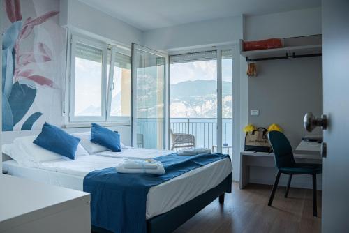 a bedroom with a bed with blue sheets and a window at Hotel Casa Marinella in Malcesine