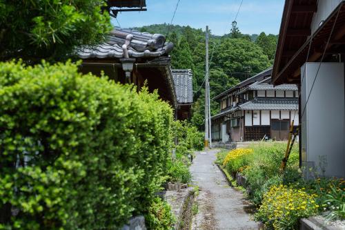 an alley with bushes and a building and a house at ゲストハウス五郎平 in Nagahama