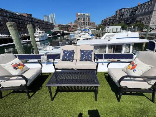 a patio with three chairs and a table and a boat at Endless Summer Oceanside Views in Boston