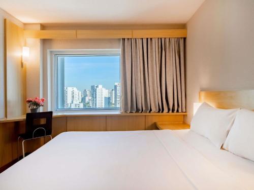 a bedroom with a large white bed and a window at ibis Sao Paulo Congonhas in São Paulo