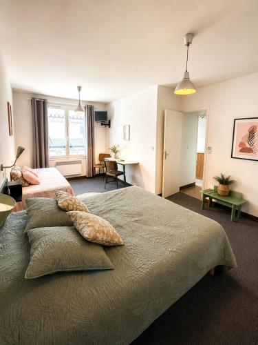 a large bedroom with two beds and a desk at Hôtel La Coursive Oléron in Saint-Pierre-dʼOléron