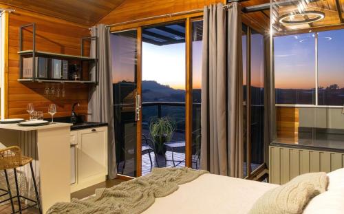 a room with a bed and a kitchen with a balcony at Cabana Altavista in Flores da Cunha