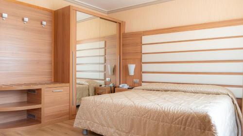 a bedroom with a bed and a desk and a mirror at Hotel Vela d'Oro Dependence in Bardolino