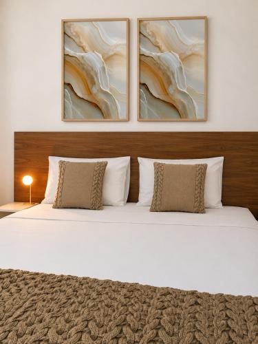 a bedroom with a bed with three paintings on the wall at Pousada Casa da Adriana in Fortaleza