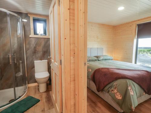 a bedroom with a bed and a shower in a cabin at Alken The Stag in Bushmills