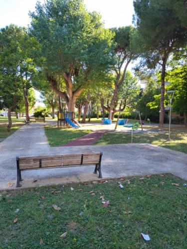 a park bench in a park with a playground at Il sorriso romagnolo in Misano Adriatico